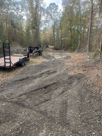 A trailer is parked on the side of a dirt road in the woods.
