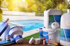 A table topped with swimming pool supplies and a swimming pool in the background.