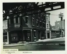 A black and white photo of a building under a bridge.