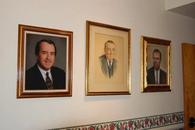 Three framed portraits of men are hanging on a wall