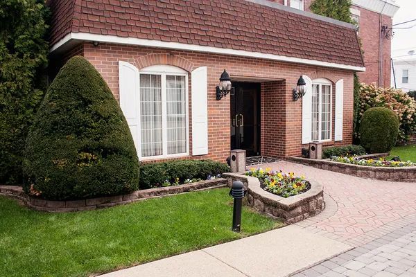 A brick house with white shutters and a walkway leading to the front door.