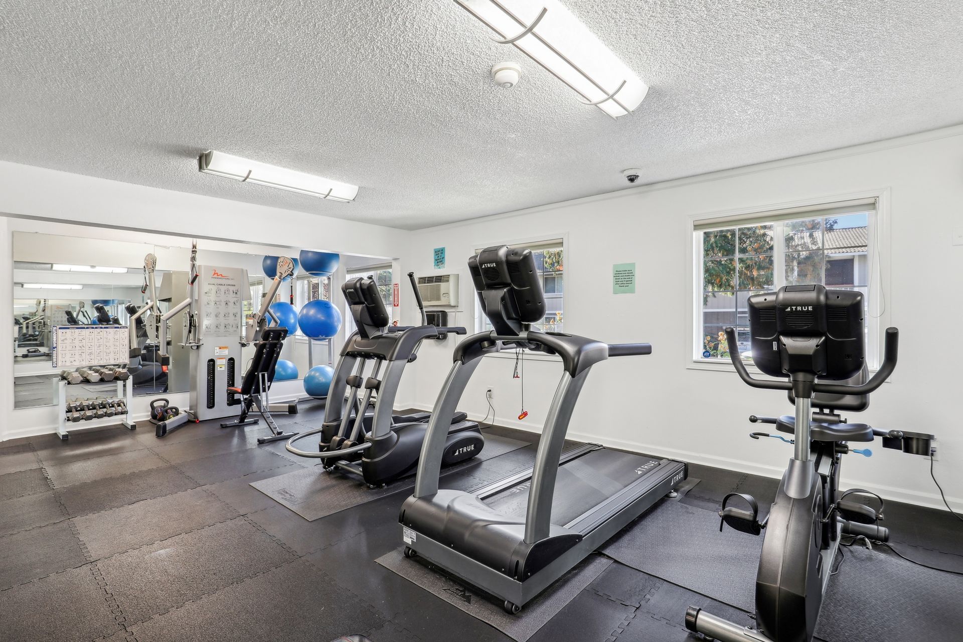 Indoor fitness center with treadmills, stationary bikes, and free weights.