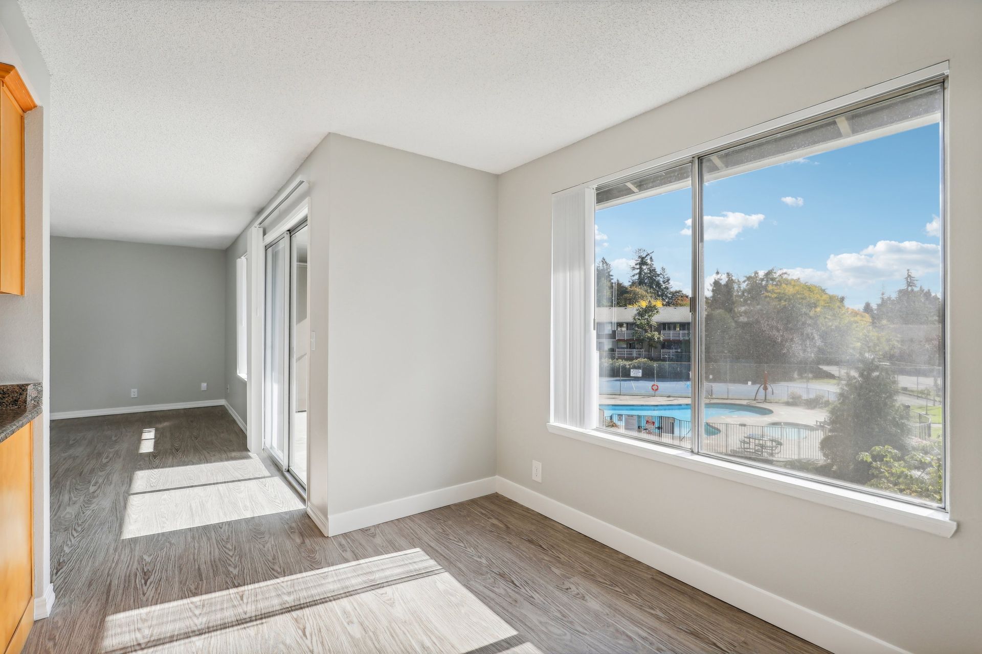 Bright living area with a large window and sliding glass door to outdoor space, pool view.