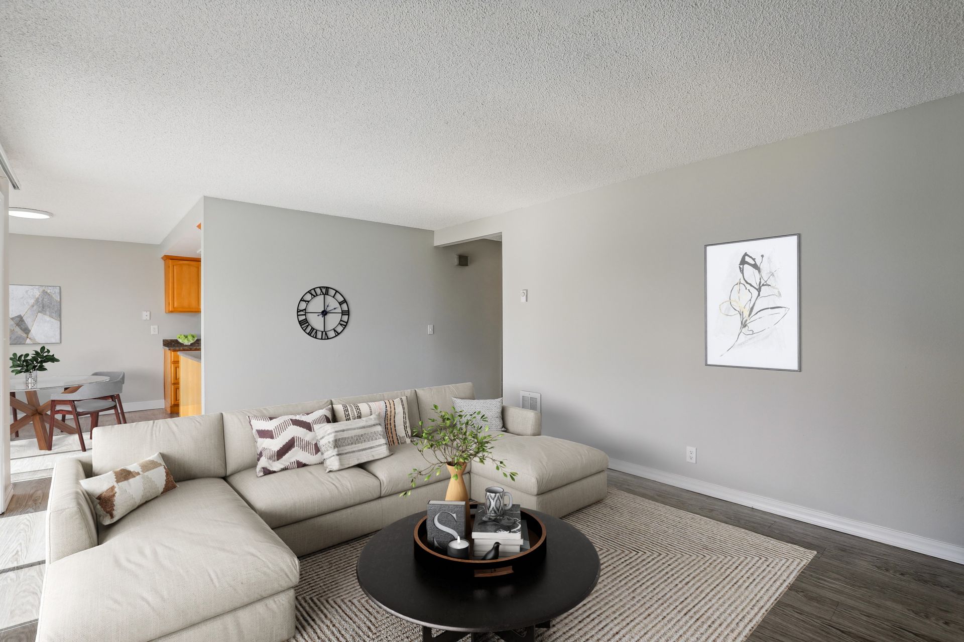 Living room in a modern apartment with a beige sectional sofa, coffee table, and wall art.