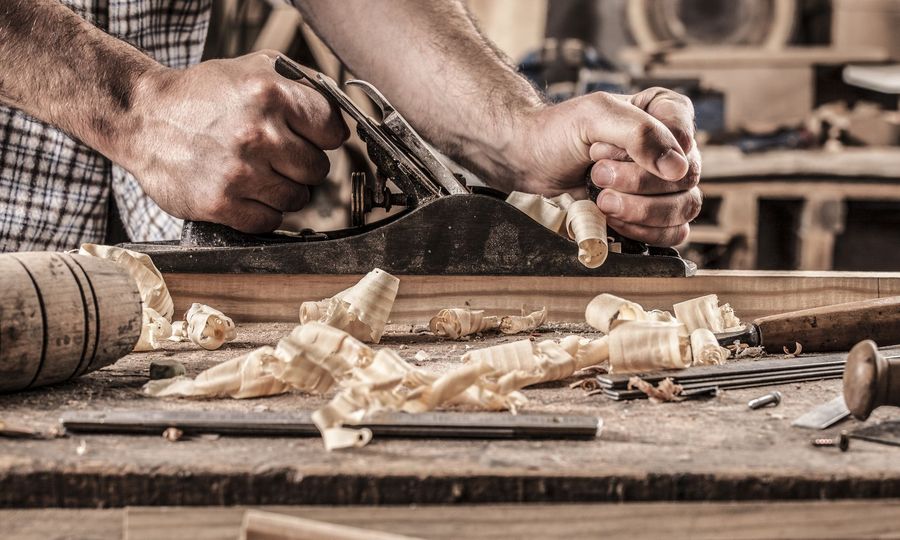 A man is using a plane to plane a piece of wood.