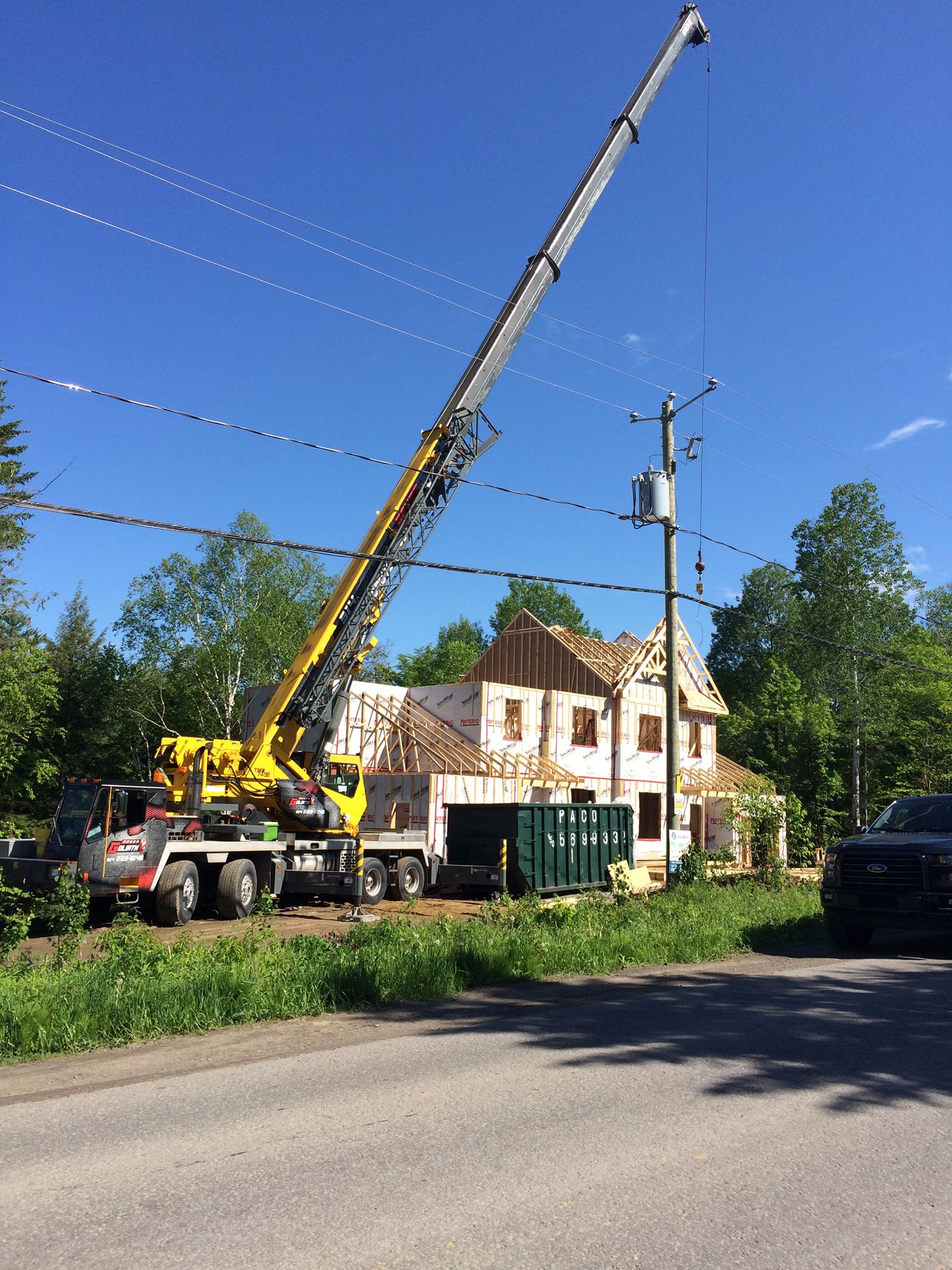 Chantier de construction avec grue pour le levage de matériaux. Maison en construction avec ossature bois. Ciel bleu.