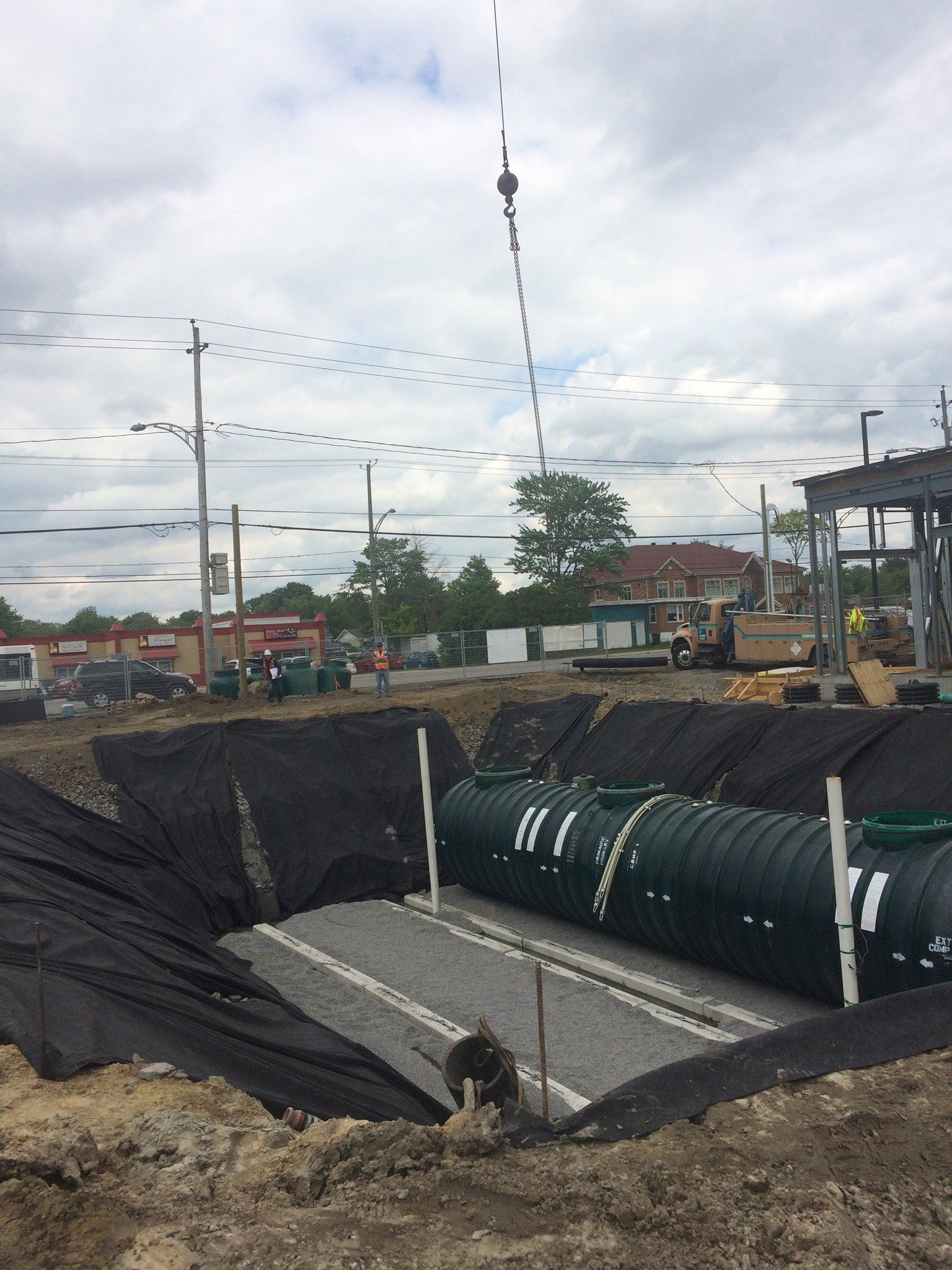 Grue abaissant une fosse septique dans une fosse préparée recouverte de gravier sur un chantier de construction.