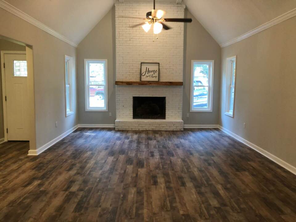An empty living room with a fireplace and a ceiling fan.