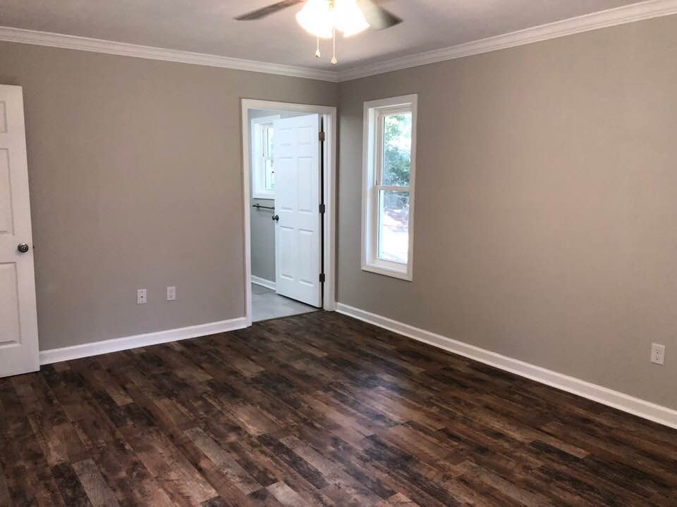 An empty room with hardwood floors and a ceiling fan.