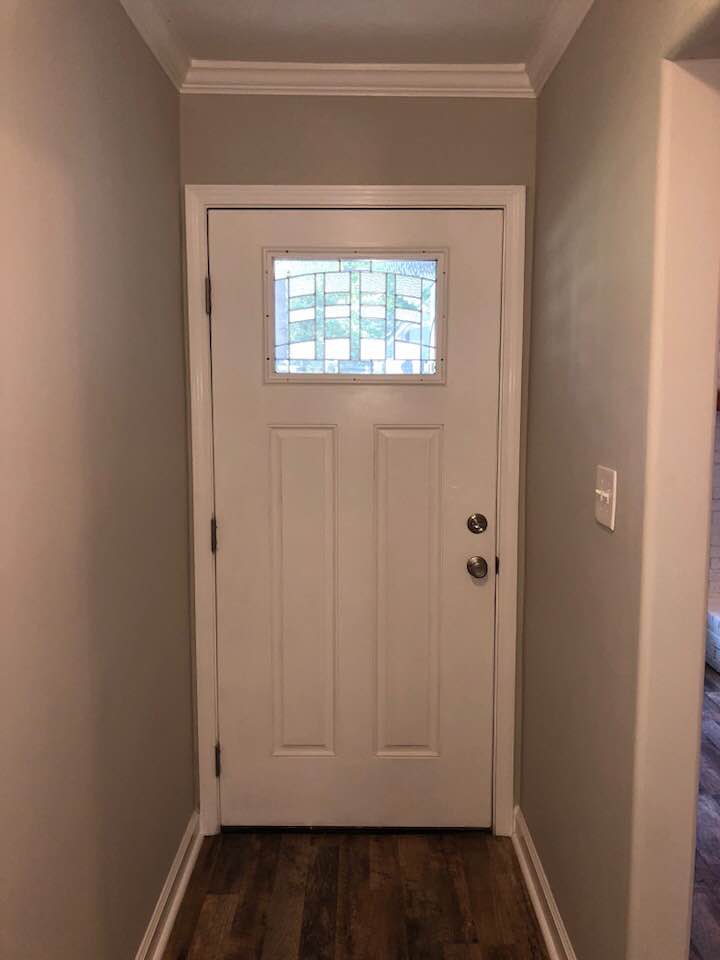 A white door with a small window in a hallway.