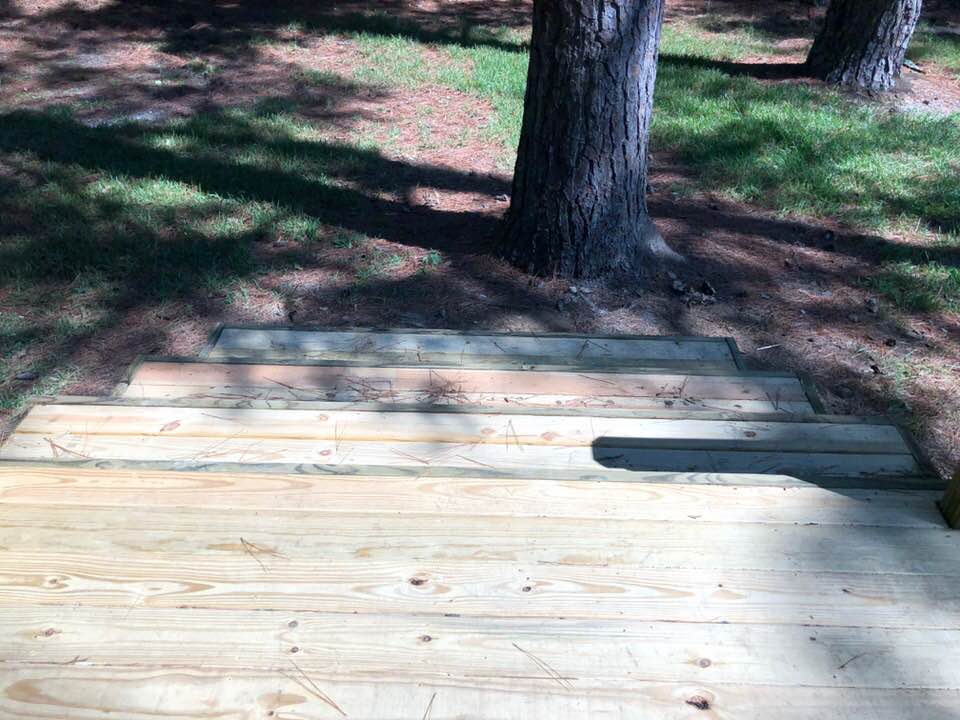 A wooden deck with stairs leading up to it in a park.