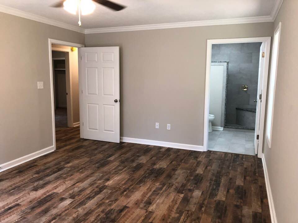 An empty bedroom with hardwood floors and a ceiling fan.