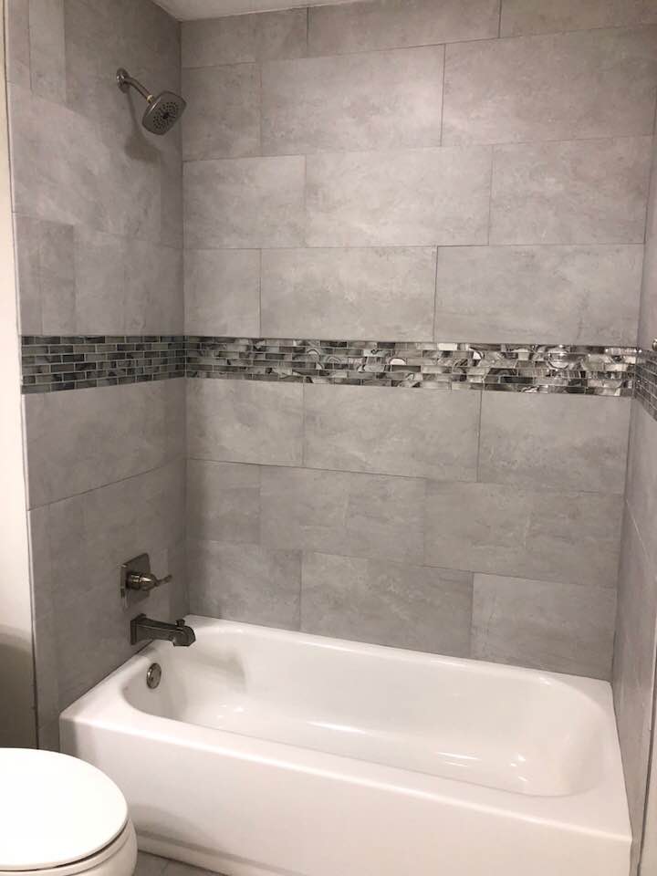 A bathroom with a bathtub , toilet and shower.