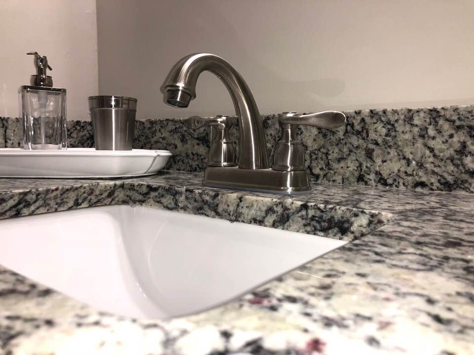A bathroom sink with a stainless steel faucet on a granite counter top.