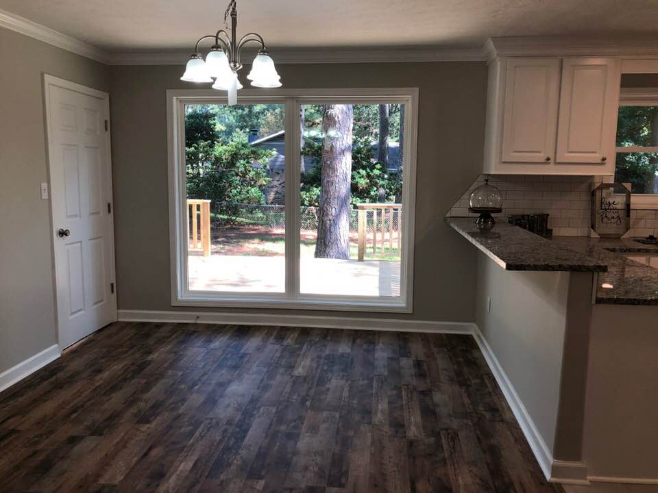 An empty dining room with hardwood floors and a sliding glass door leading to a deck.