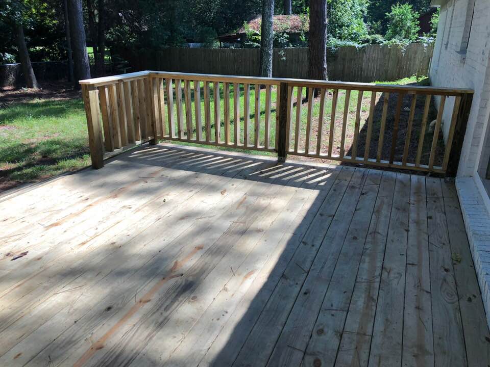 A wooden deck with a railing in the backyard