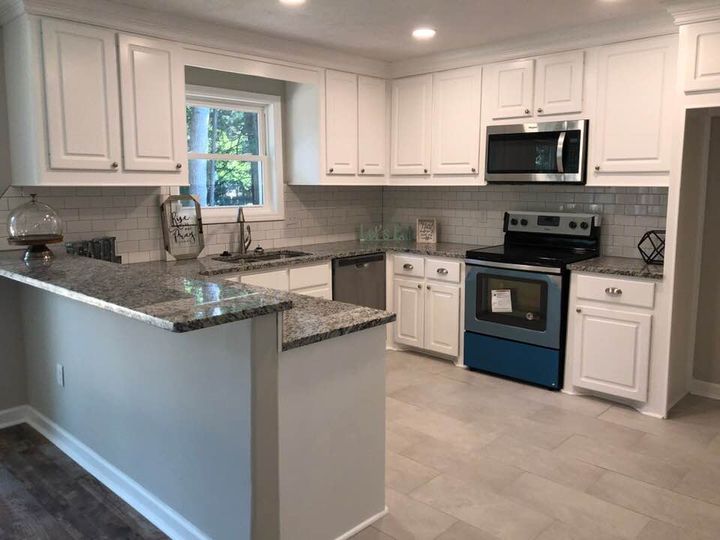 A kitchen with white cabinets , stainless steel appliances and granite counter tops.