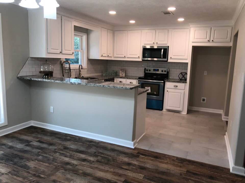 A kitchen with white cabinets , granite counter tops , stainless steel appliances , and hardwood floors.