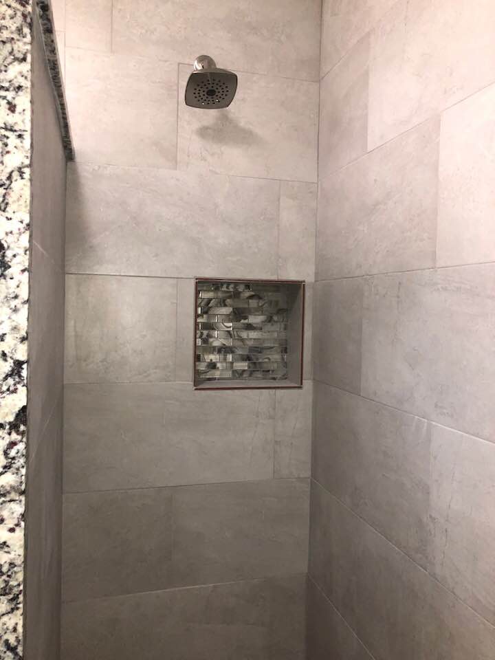 A shower with a shower head and a niche in the wall.