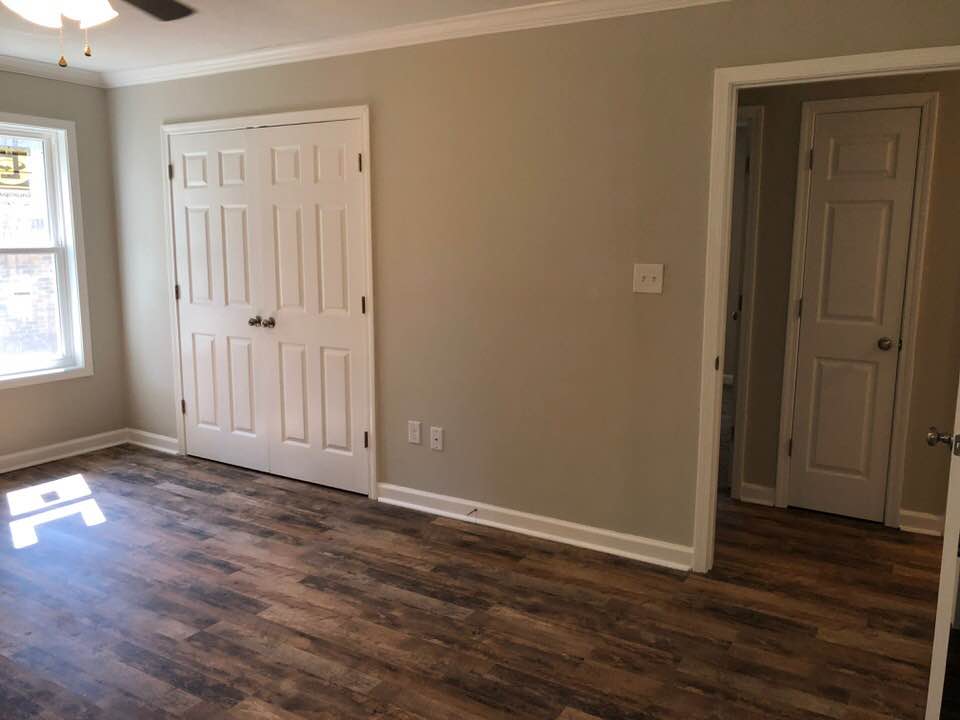 An empty bedroom with hardwood floors and a ceiling fan.