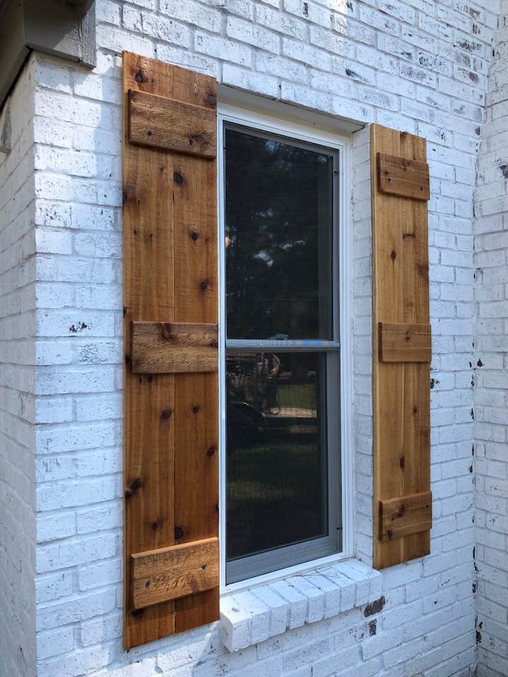 A window with wooden shutters on a white brick wall.