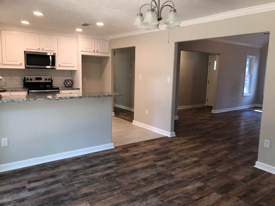 A kitchen and dining room in a house with hardwood floors and white cabinets.