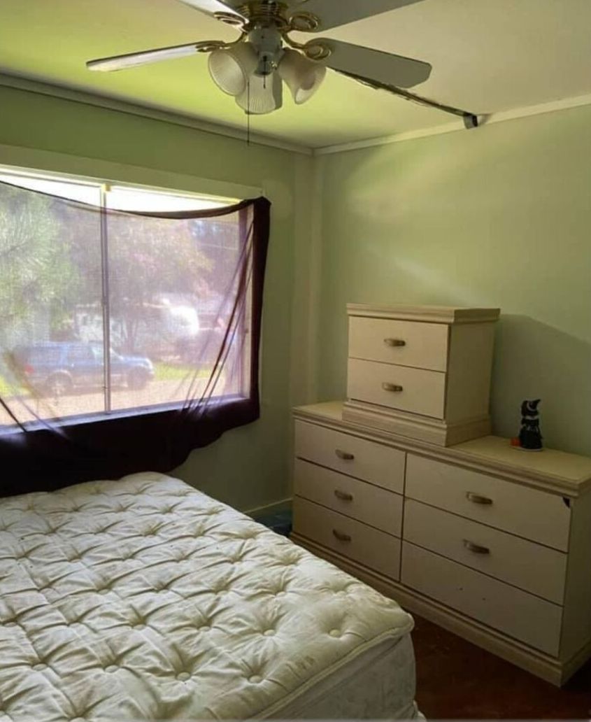 A bedroom with a bed and a ceiling fan