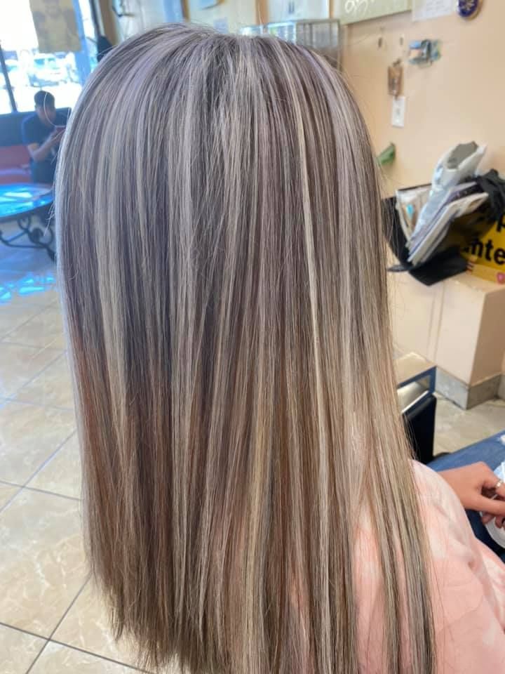 Woman with long, straight hair featuring highlights of blonde, gray, and brown colors.