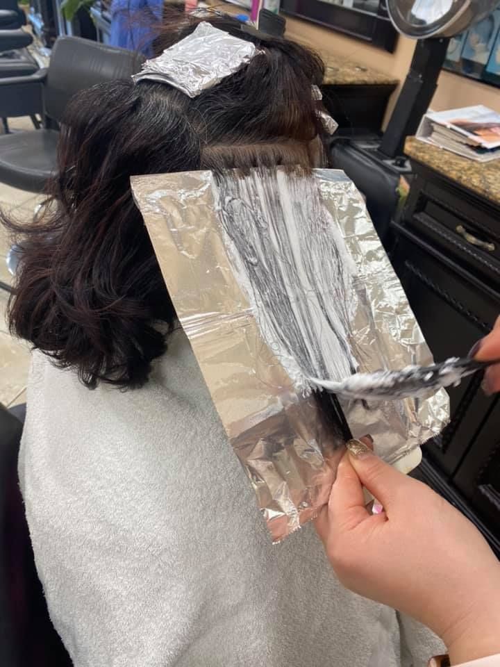Hairdresser applying bleach to dark hair using foil.