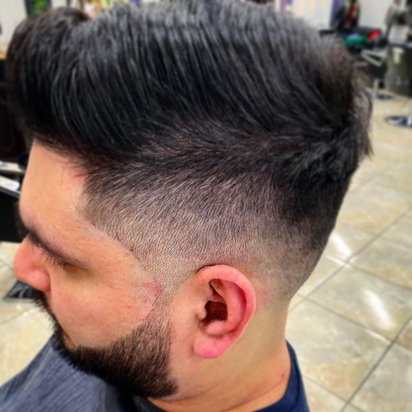Man with dark hair and beard, fade haircut, styled up.