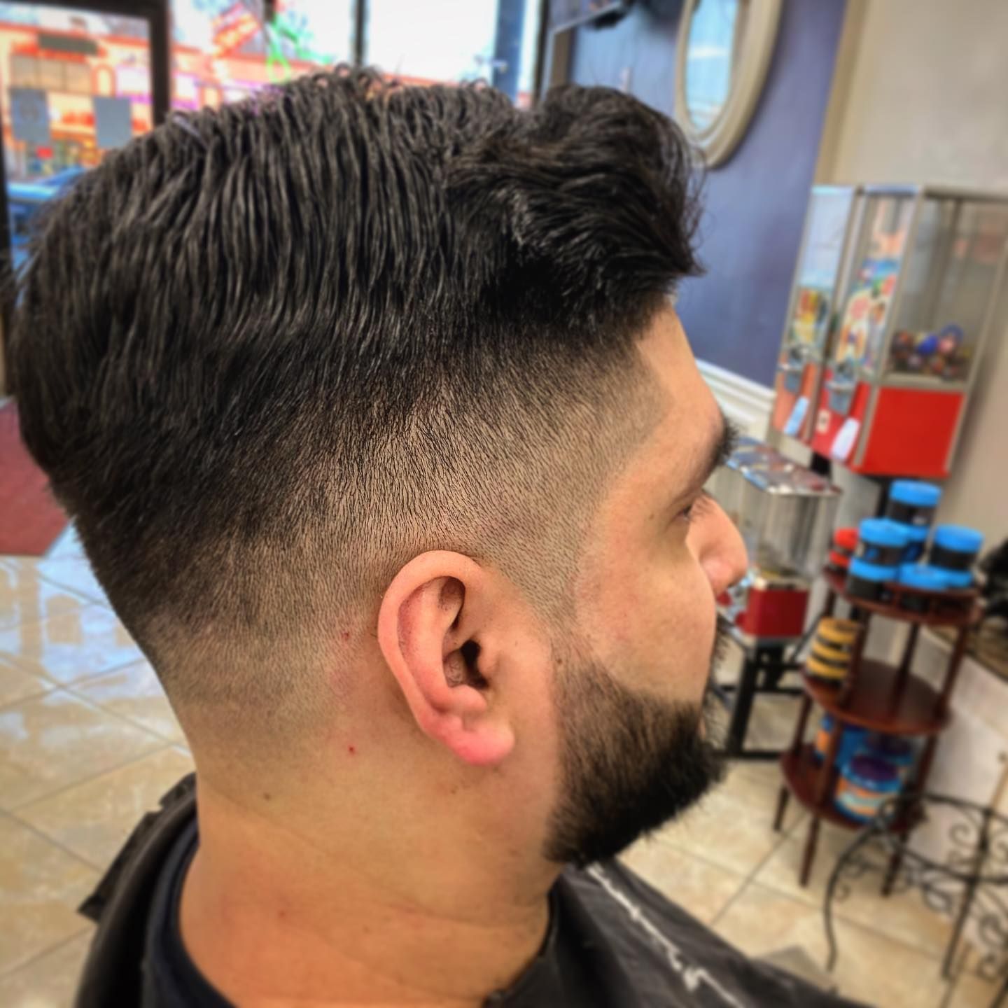 Man with a fade haircut and beard in a barber shop.