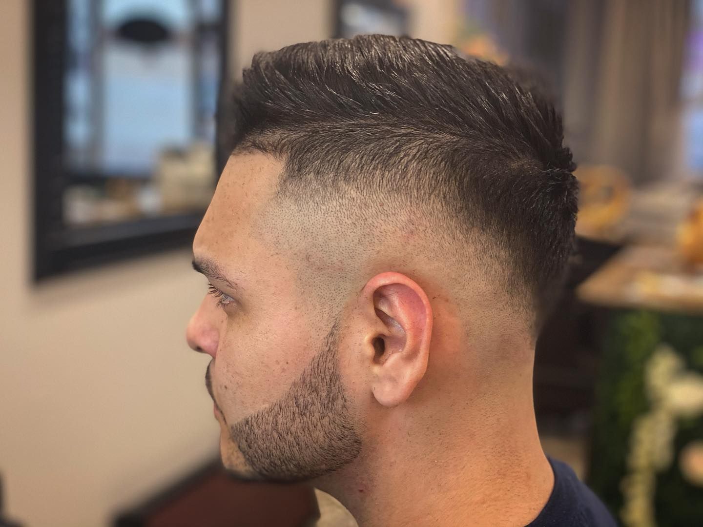 Man with fade haircut and short beard, facing left.