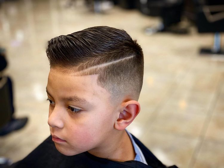 Boy with a side part and faded haircut, looking to the side.