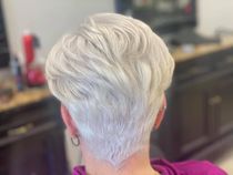 Back view of a person with short, layered, platinum blonde hair and a tapered nape.