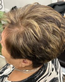 Woman with short, layered hairstyle featuring brown and blonde highlights.