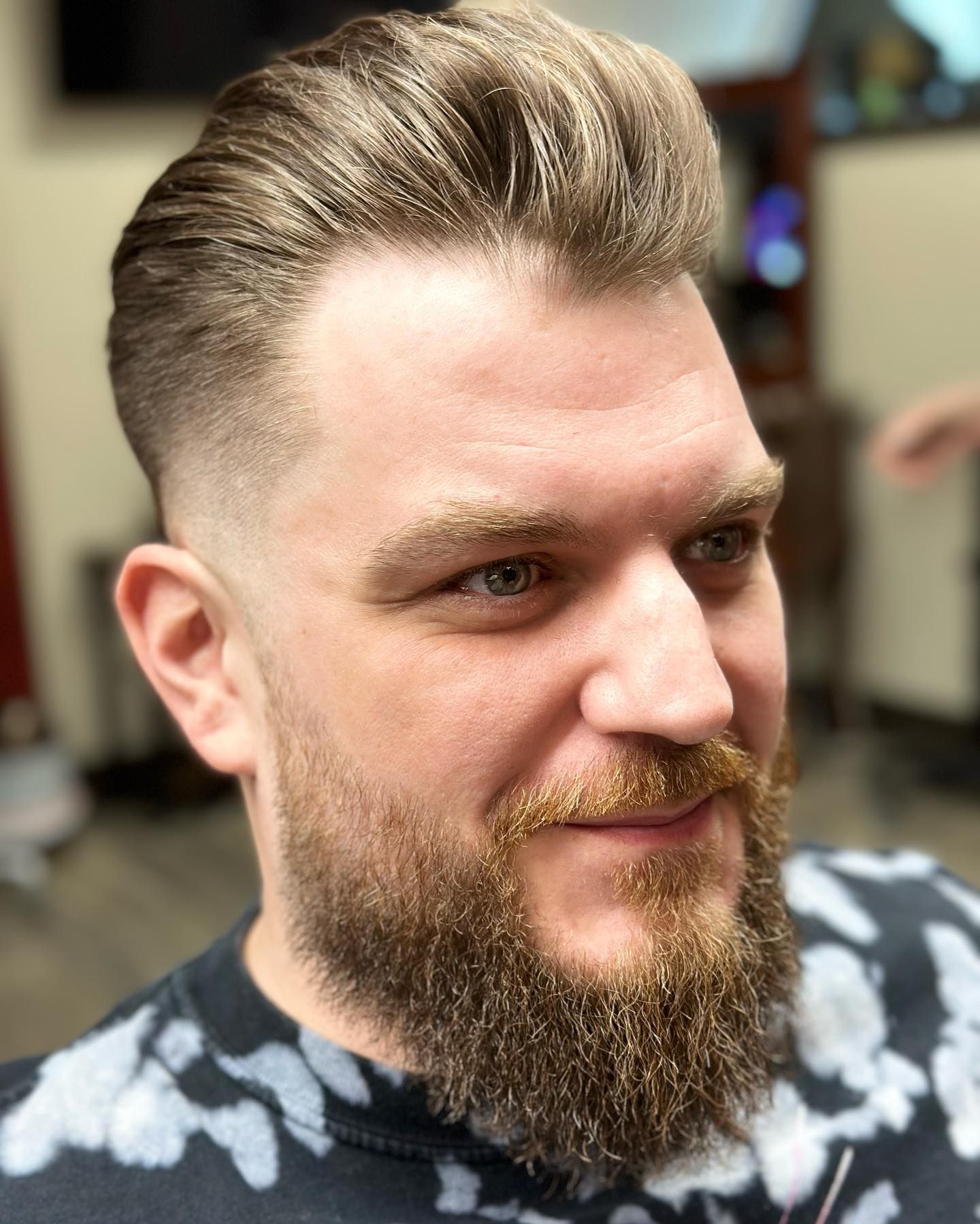 Man with blonde hair and beard, faded sides, looking to the side.