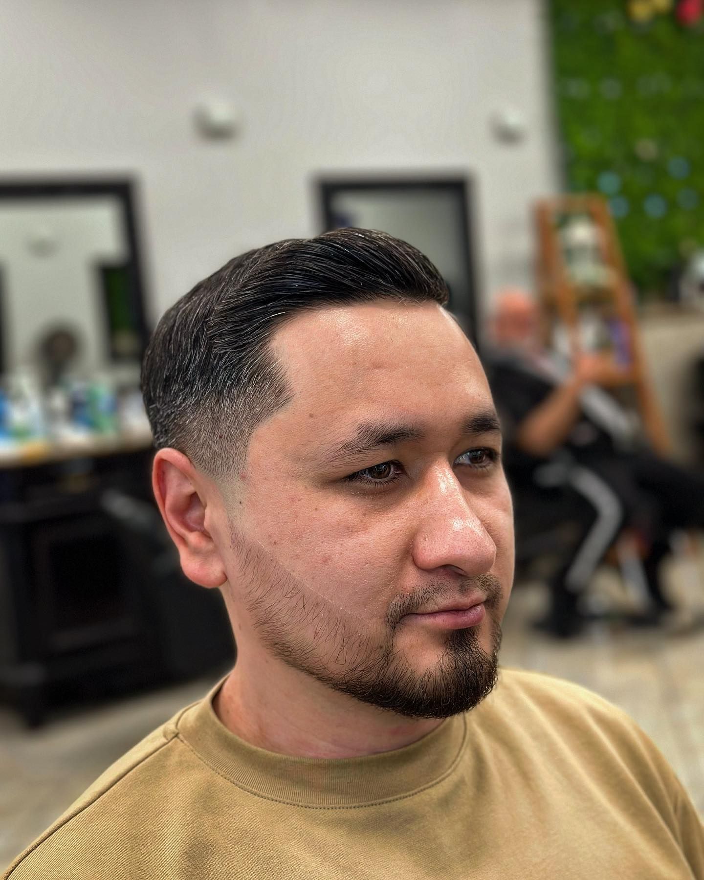 Man with short dark hair and a faded haircut at a barbershop, looking right.