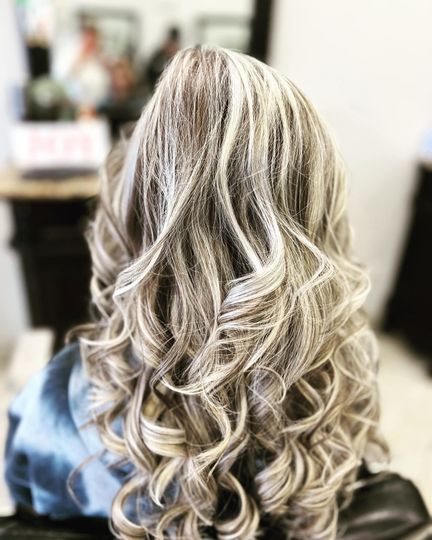 Woman with wavy, highlighted blonde and brown hair in a salon.