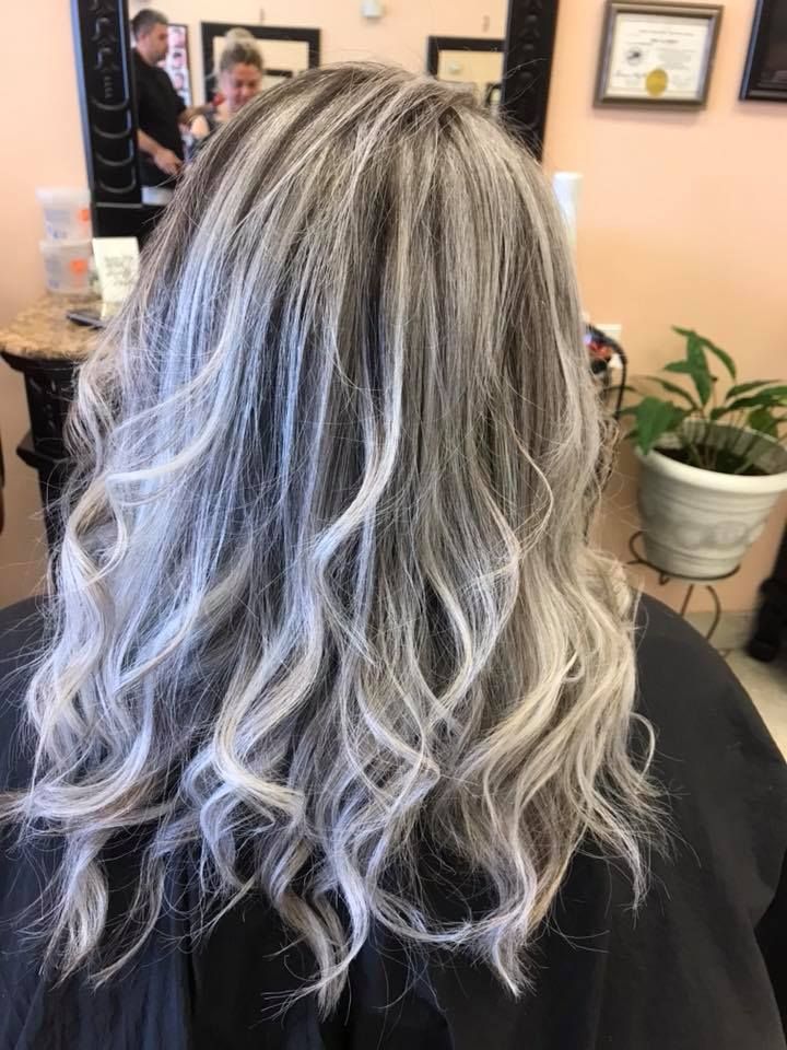Woman with wavy, gray and blonde highlighted hair at a salon.