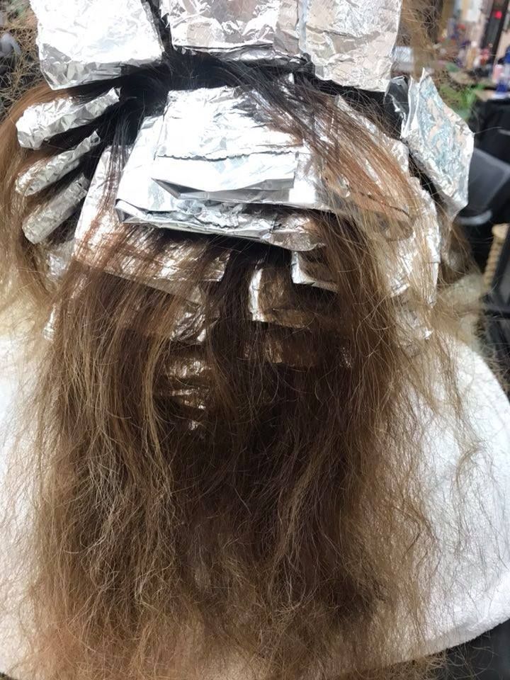Person with hair foils, undergoing hair coloring in a salon.