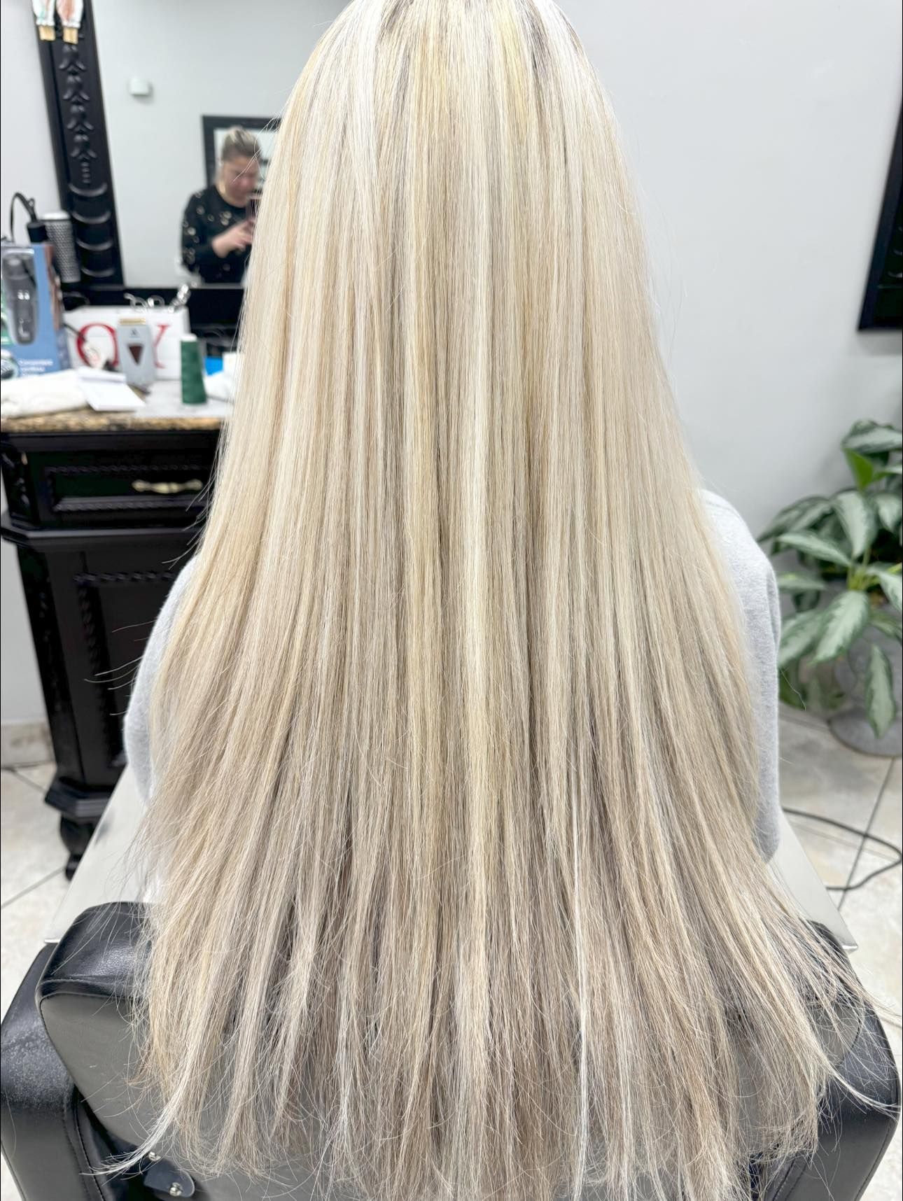 Woman with long, straight, blonde hair sitting in a salon chair.