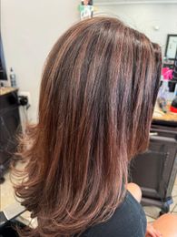 Woman with layered, brown hair in a salon.