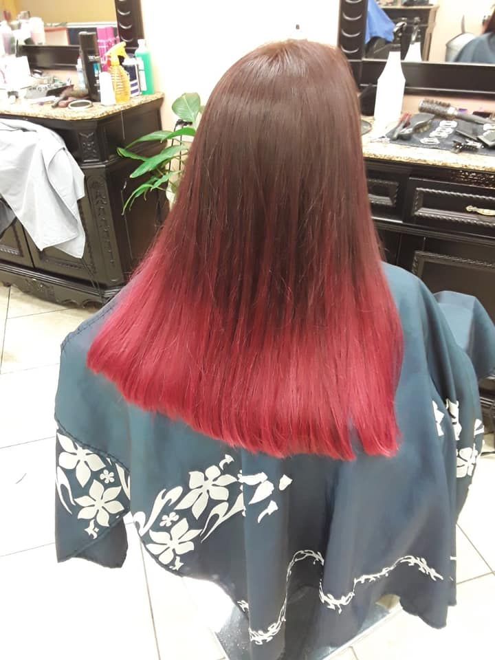 Woman with long, dark-brown hair fading to a bright red at the tips, seated in a salon.