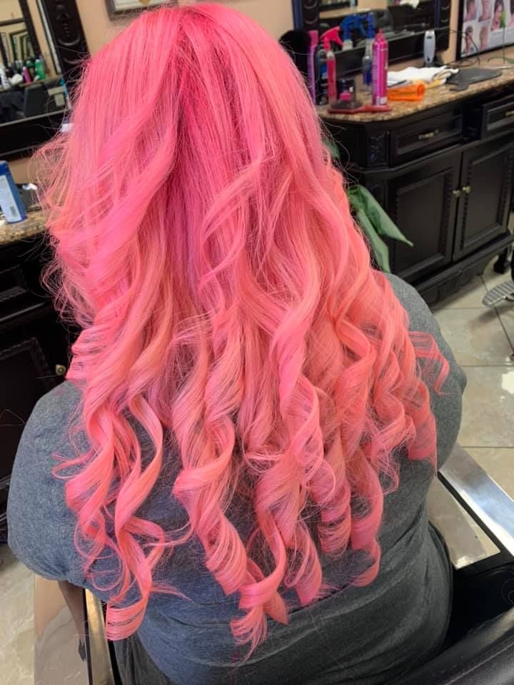 Woman with vibrant pink, curly hair in a salon.