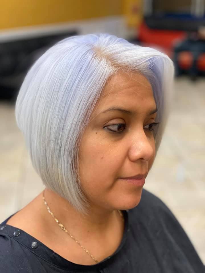 Woman with a short, silver bob haircut and a touch of blue.  She's wearing a black top and a gold chain.
