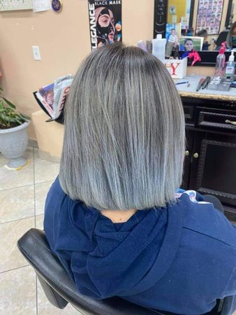 Woman with gray hair and a blue ombre bob cut sits in a salon chair.