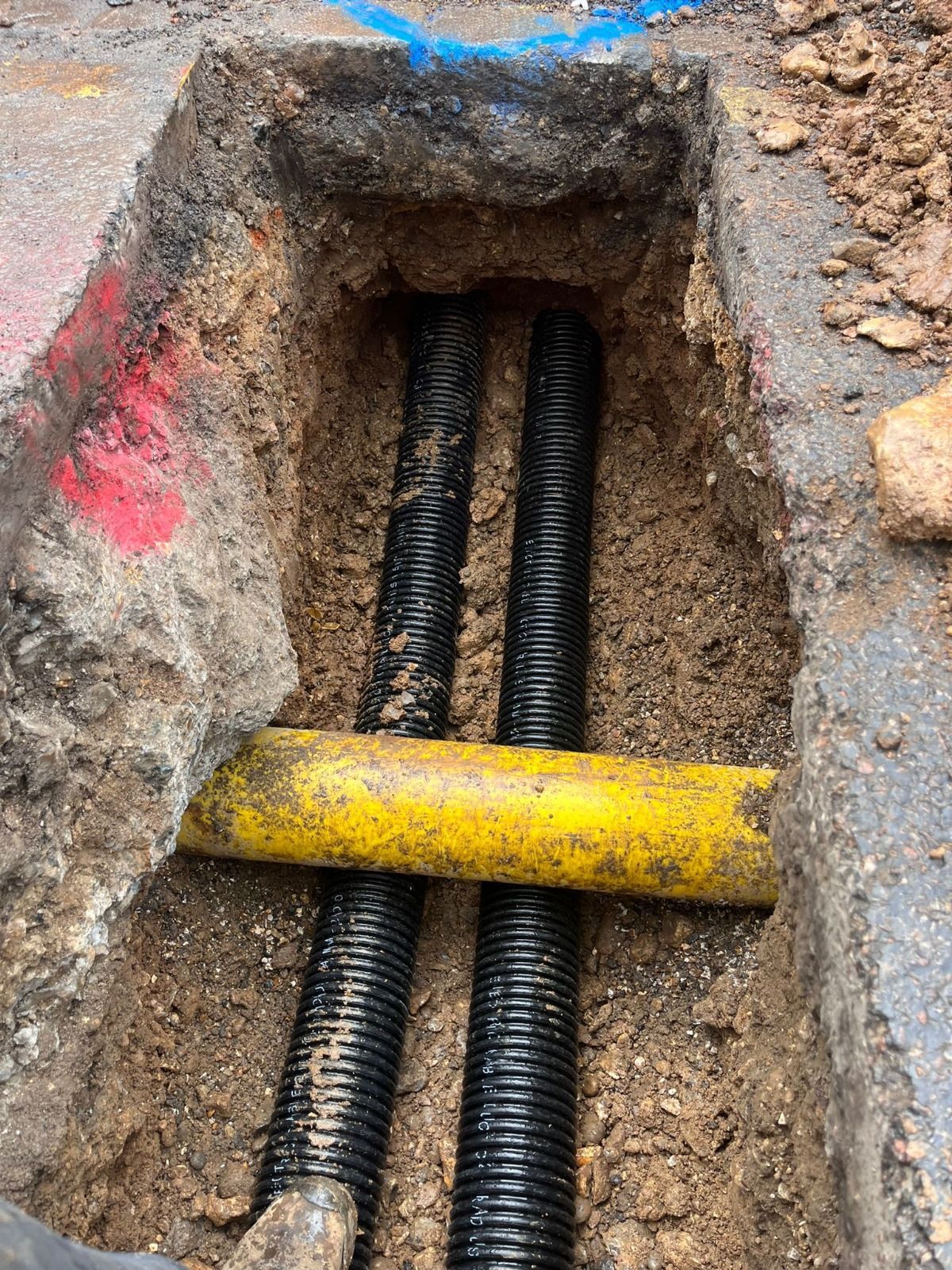 A yellow pipe is sticking out of a hole in the ground.