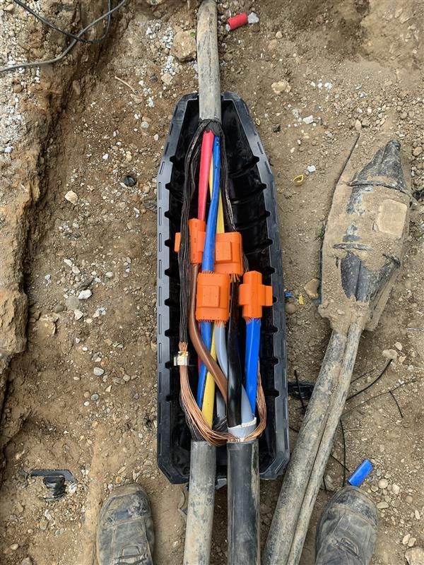A bunch of wires are in a plastic box on the ground.