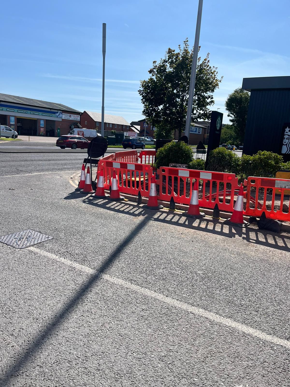 A row of orange and white traffic cones are sitting on the side of a road.
