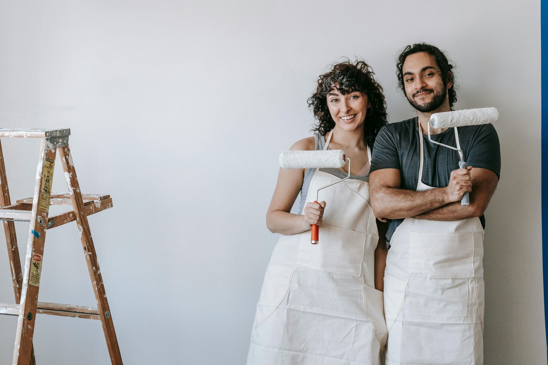 two people holding up paint rollers in front of a white wall